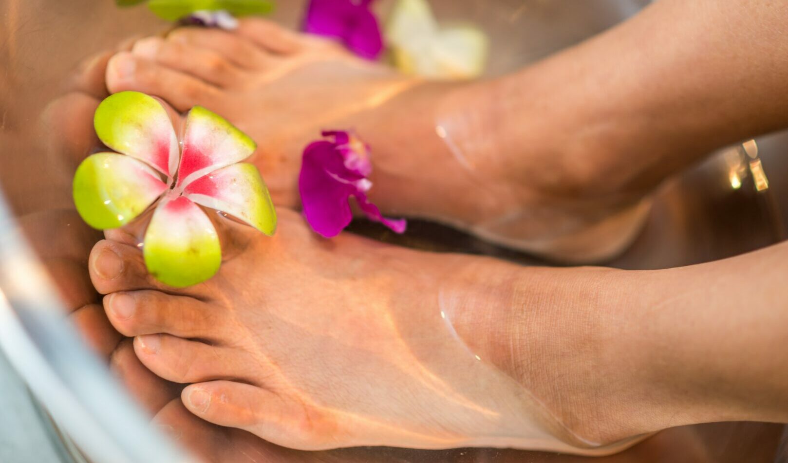 Füße in Wasser mit Blumen für Wellness.